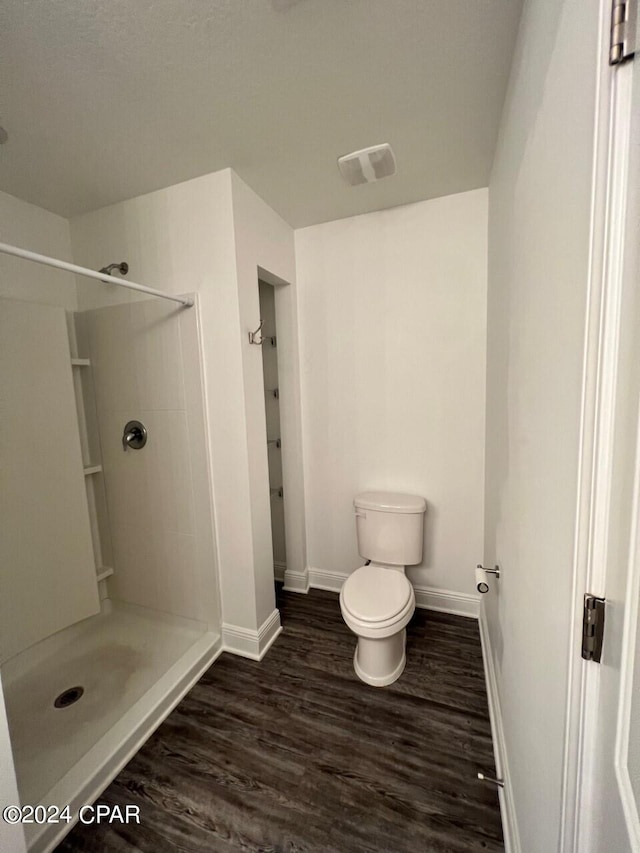 bathroom with toilet, hardwood / wood-style floors, and a shower