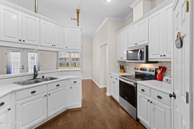 kitchen with sink, appliances with stainless steel finishes, white cabinets, and crown molding