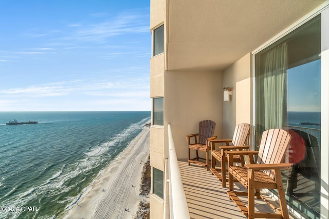 balcony with a water view and a view of the beach