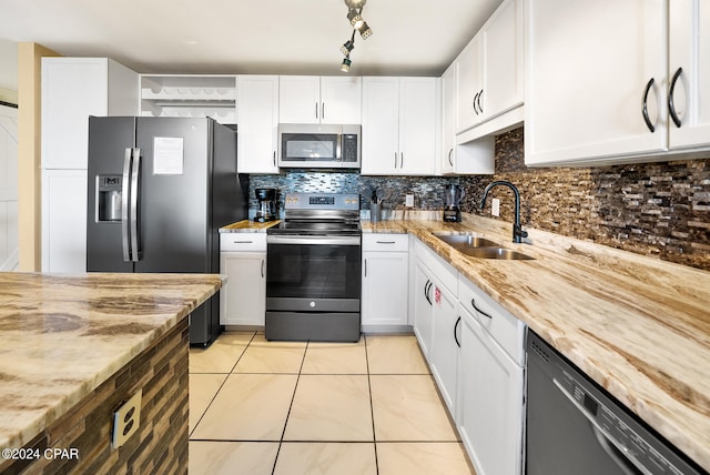 kitchen featuring light tile flooring, backsplash, appliances with stainless steel finishes, and white cabinetry