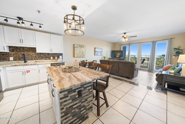 kitchen featuring a breakfast bar area, light tile patterned flooring, open floor plan, and backsplash