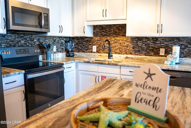 kitchen featuring a sink, white cabinets, backsplash, and stainless steel appliances