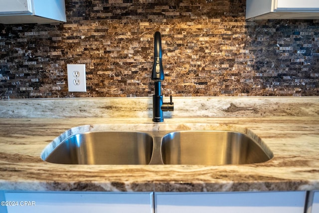 details with a sink, light stone counters, backsplash, and white cabinets