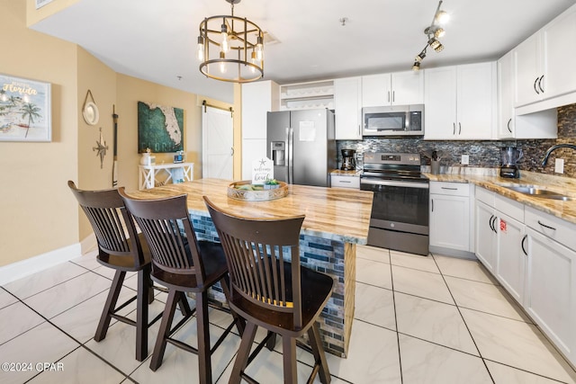 kitchen featuring a sink, a barn door, backsplash, and stainless steel appliances