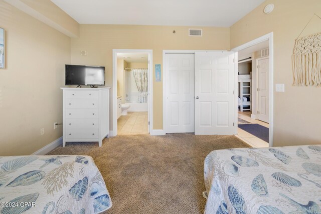 bedroom with a closet, connected bathroom, and light carpet