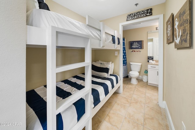 bedroom featuring light tile patterned floors, connected bathroom, and baseboards