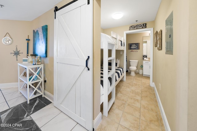 corridor featuring a barn door, electric panel, baseboards, and marble finish floor