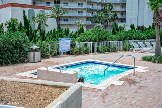 view of swimming pool featuring a patio area, fence, and a hot tub