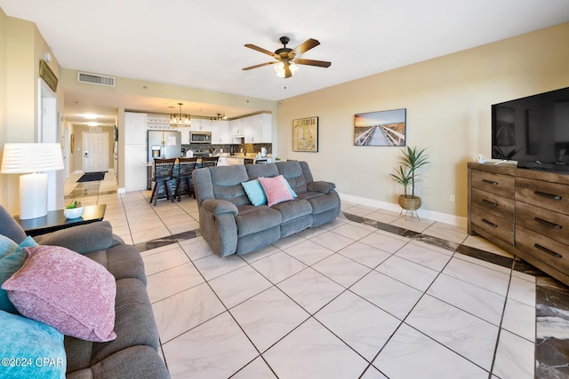 living room featuring light tile patterned flooring, visible vents, ceiling fan with notable chandelier, and baseboards