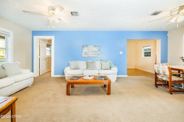 carpeted living room with a textured ceiling and ceiling fan