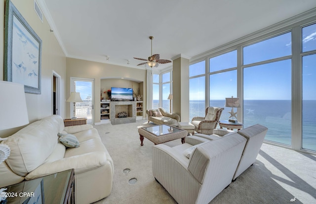 carpeted living room featuring visible vents, ceiling fan, a fireplace with flush hearth, and crown molding