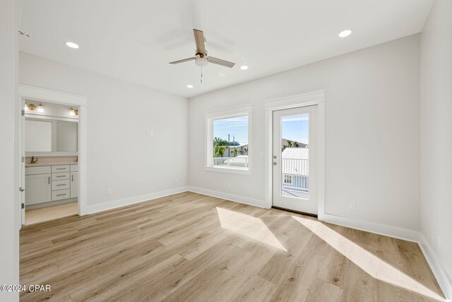 unfurnished bedroom featuring access to exterior, connected bathroom, ceiling fan, and light wood-type flooring