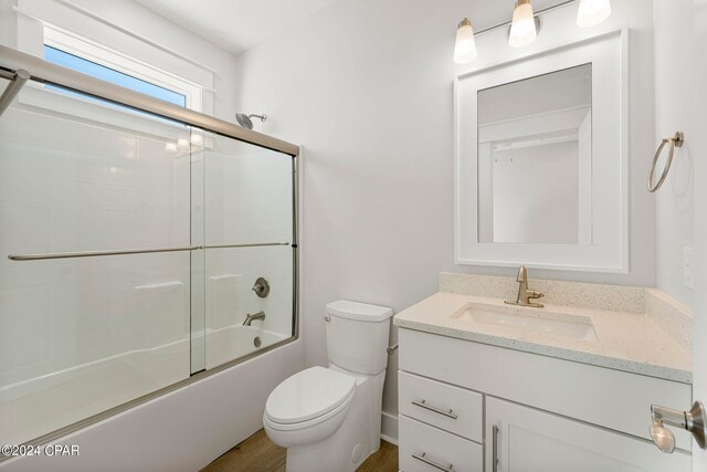 full bathroom featuring shower / bath combination with glass door, large vanity, and toilet