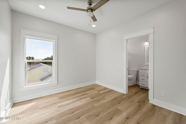 unfurnished bedroom with ensuite bath, light hardwood / wood-style floors, and ceiling fan