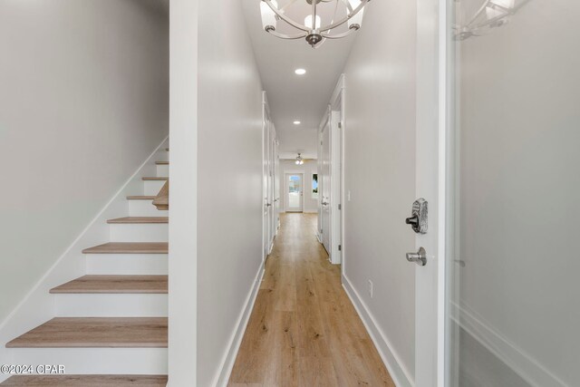 corridor featuring a notable chandelier and light wood-type flooring