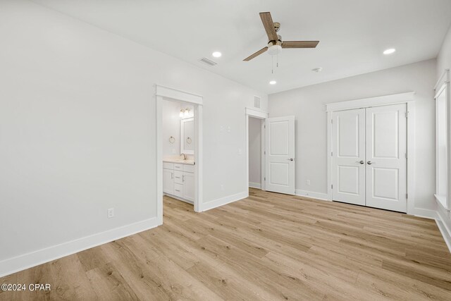 unfurnished bedroom featuring connected bathroom, ceiling fan, a closet, light wood-type flooring, and sink