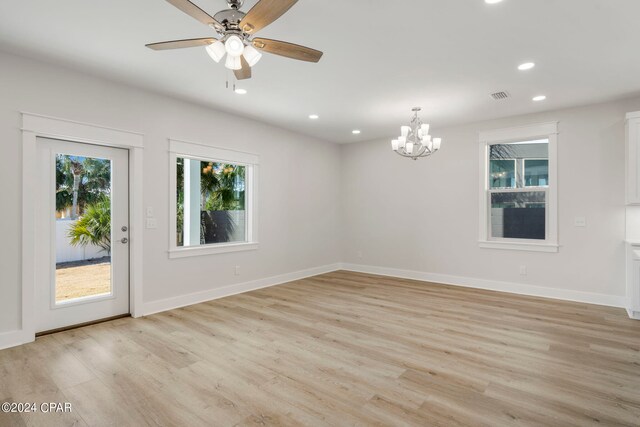 unfurnished room featuring light wood-type flooring and ceiling fan with notable chandelier