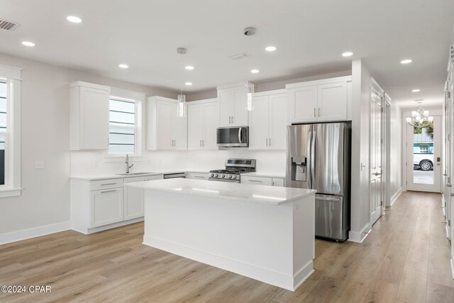 kitchen with stainless steel appliances, light wood-type flooring, white cabinetry, and a center island