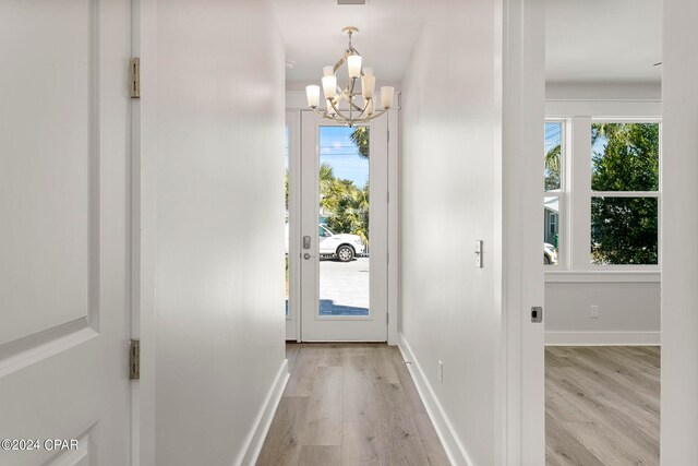 doorway featuring a notable chandelier and light wood-type flooring