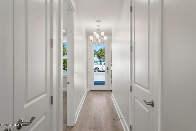 hall featuring light hardwood / wood-style flooring and an inviting chandelier