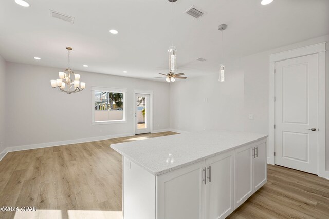 kitchen featuring light hardwood / wood-style floors, decorative light fixtures, ceiling fan with notable chandelier, white cabinets, and light stone counters