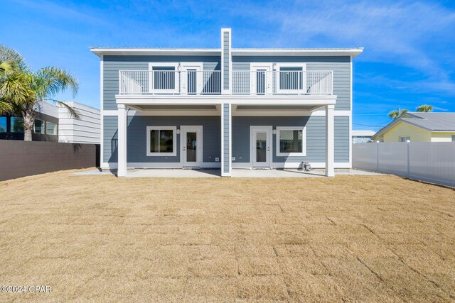 back of house featuring a balcony, a lawn, french doors, and a patio