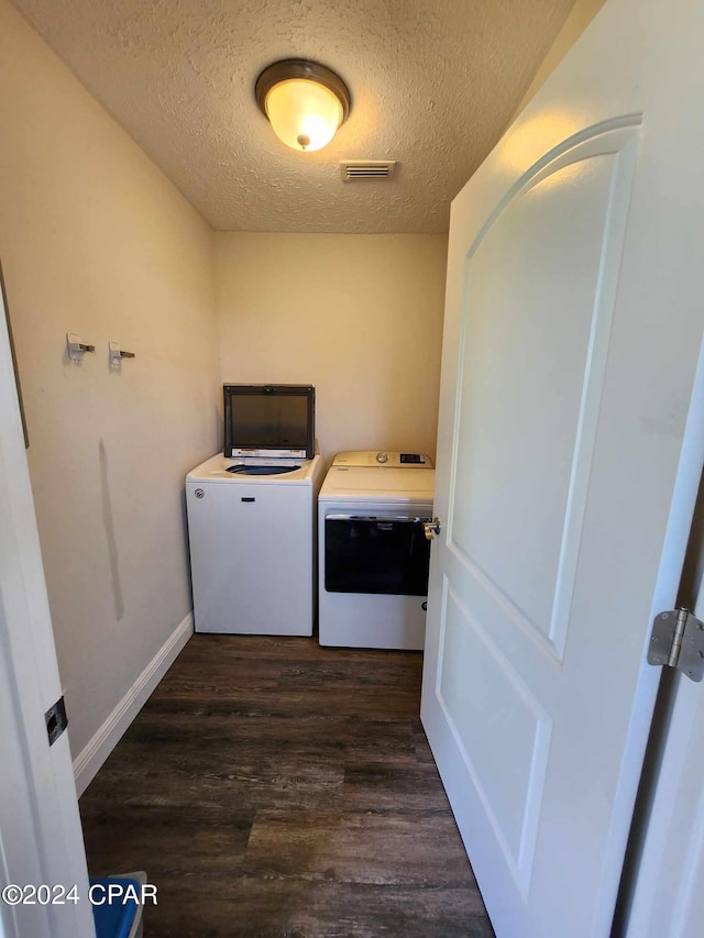 laundry room featuring washer and clothes dryer, a textured ceiling, and dark hardwood / wood-style flooring