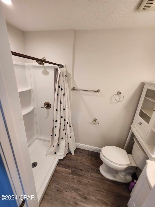 bathroom featuring wood-type flooring, toilet, and curtained shower