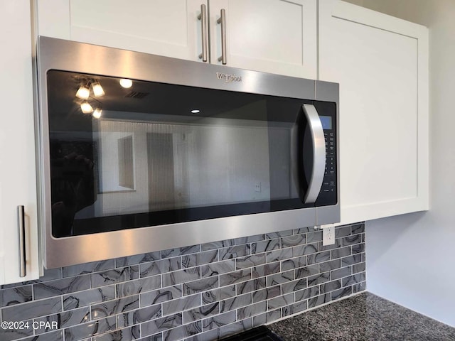 interior details featuring white cabinets and dark stone counters