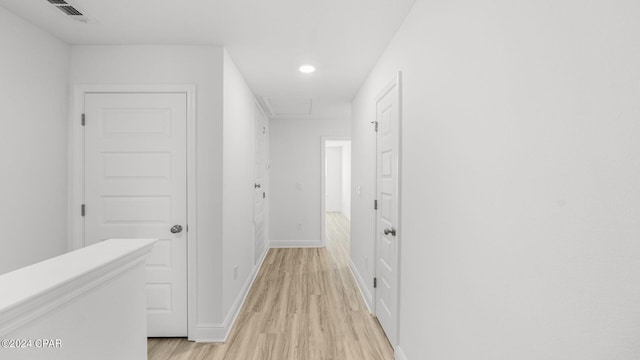 corridor featuring visible vents, light wood-style flooring, attic access, and baseboards