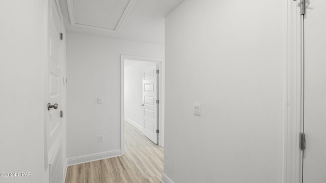 hallway featuring light wood-style flooring and baseboards