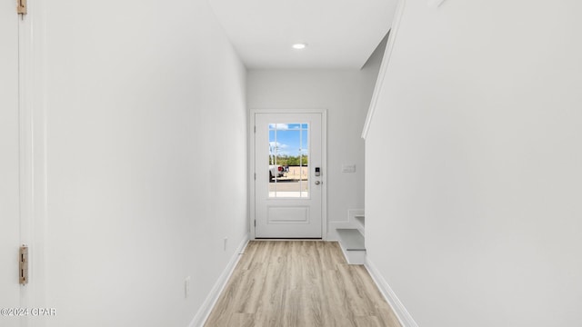 doorway to outside featuring baseboards and light wood-style flooring