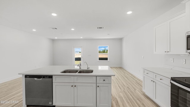 kitchen featuring light wood finished floors, light stone countertops, appliances with stainless steel finishes, white cabinetry, and a sink