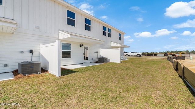 back of house featuring fence, a yard, central AC unit, and board and batten siding