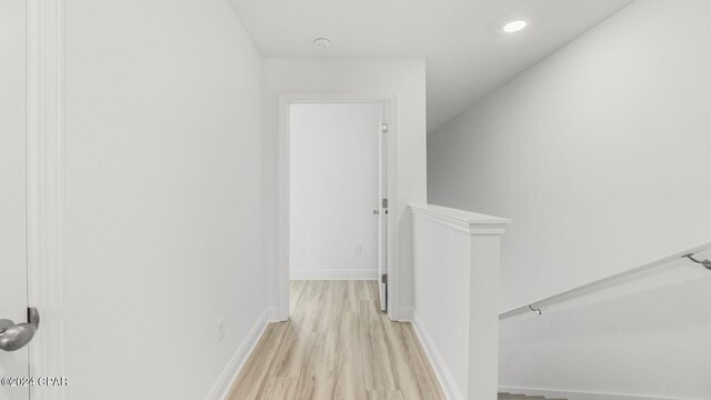 hall with an upstairs landing, recessed lighting, baseboards, and light wood-style floors