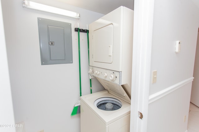 laundry room with electric panel, stacked washer / dryer, and light tile patterned floors