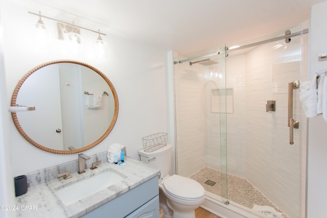 bathroom with a shower with door, toilet, and vanity