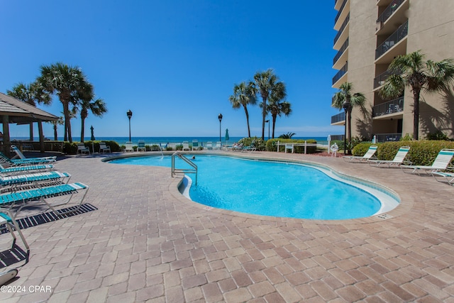 view of swimming pool with a water view and a patio