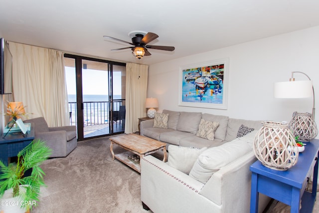 carpeted living room featuring expansive windows, a water view, and ceiling fan