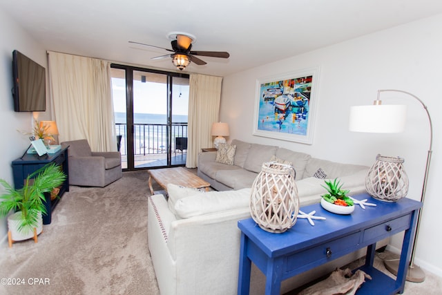 living room with ceiling fan, a water view, and light colored carpet