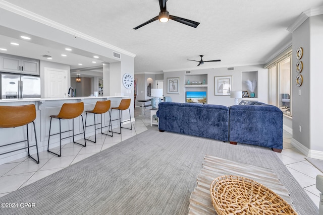 living room with ceiling fan, light tile flooring, a textured ceiling, sink, and ornamental molding