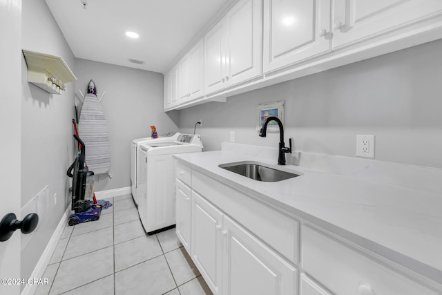 laundry area with washer and dryer, sink, light tile flooring, and cabinets