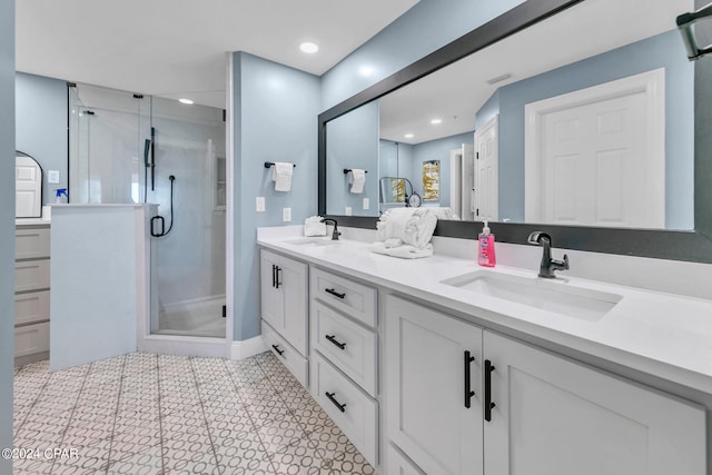 bathroom featuring a shower with shower door, double sink vanity, and tile floors