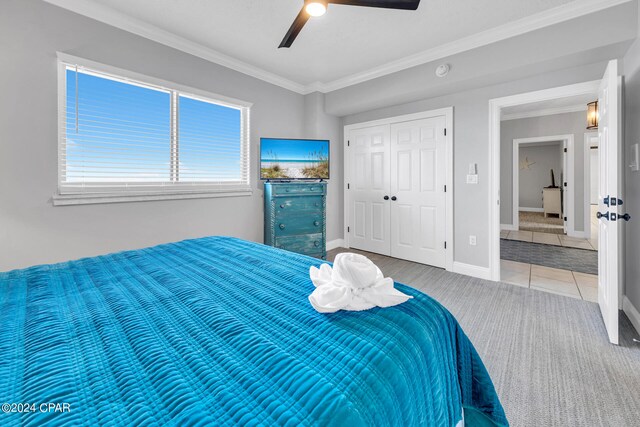 bedroom featuring ornamental molding, a closet, carpet, and ceiling fan