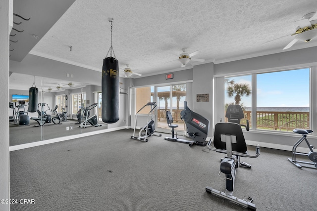 workout area featuring ceiling fan, a textured ceiling, and ornamental molding