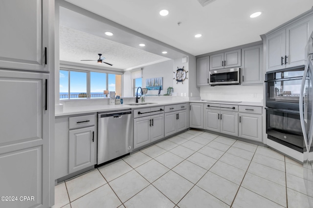 kitchen featuring ceiling fan, light tile floors, appliances with stainless steel finishes, sink, and a textured ceiling