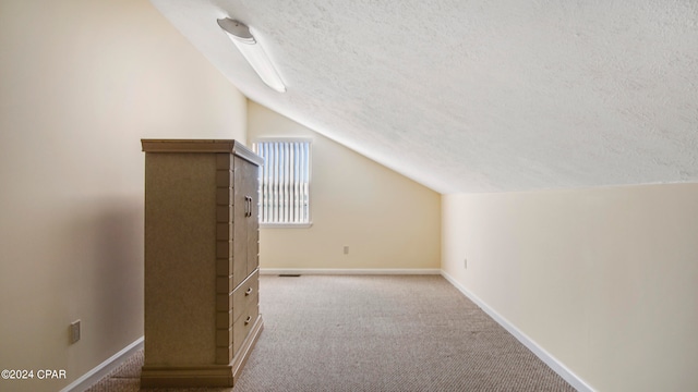 additional living space with carpet, a textured ceiling, and vaulted ceiling