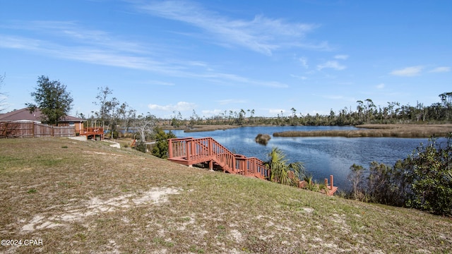 view of dock with a water view and a yard