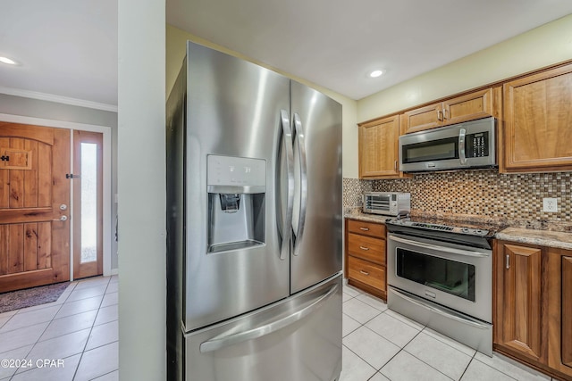 kitchen featuring light tile patterned flooring, ornamental molding, appliances with stainless steel finishes, and stone countertops