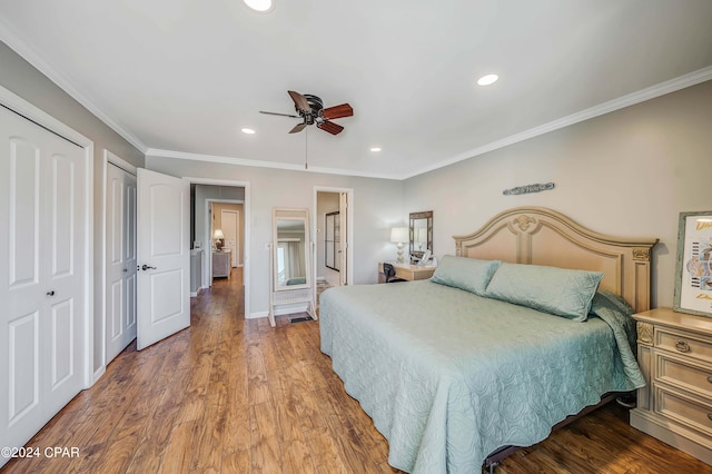 bedroom with ceiling fan, hardwood / wood-style flooring, two closets, and ornamental molding